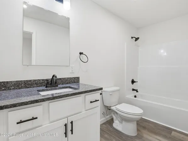 a bathroom with a granite countertop toilet a sink and a mirror