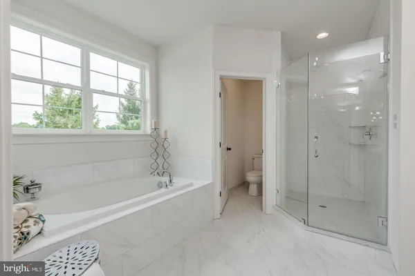 a spacious bathroom with a granite countertop sink a large mirror a bathtub and next to a window