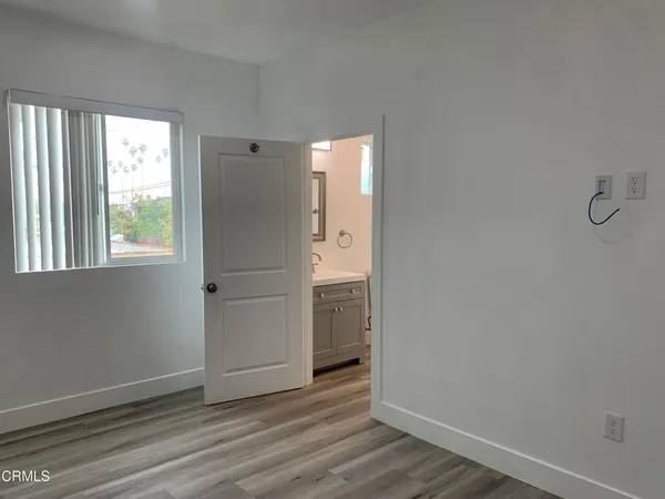 an empty room with wooden floor cabinet and windows