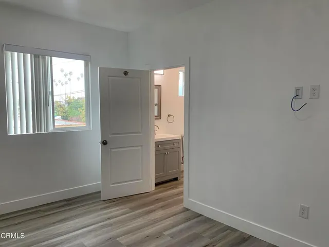 an empty room with wooden floor cabinet and windows