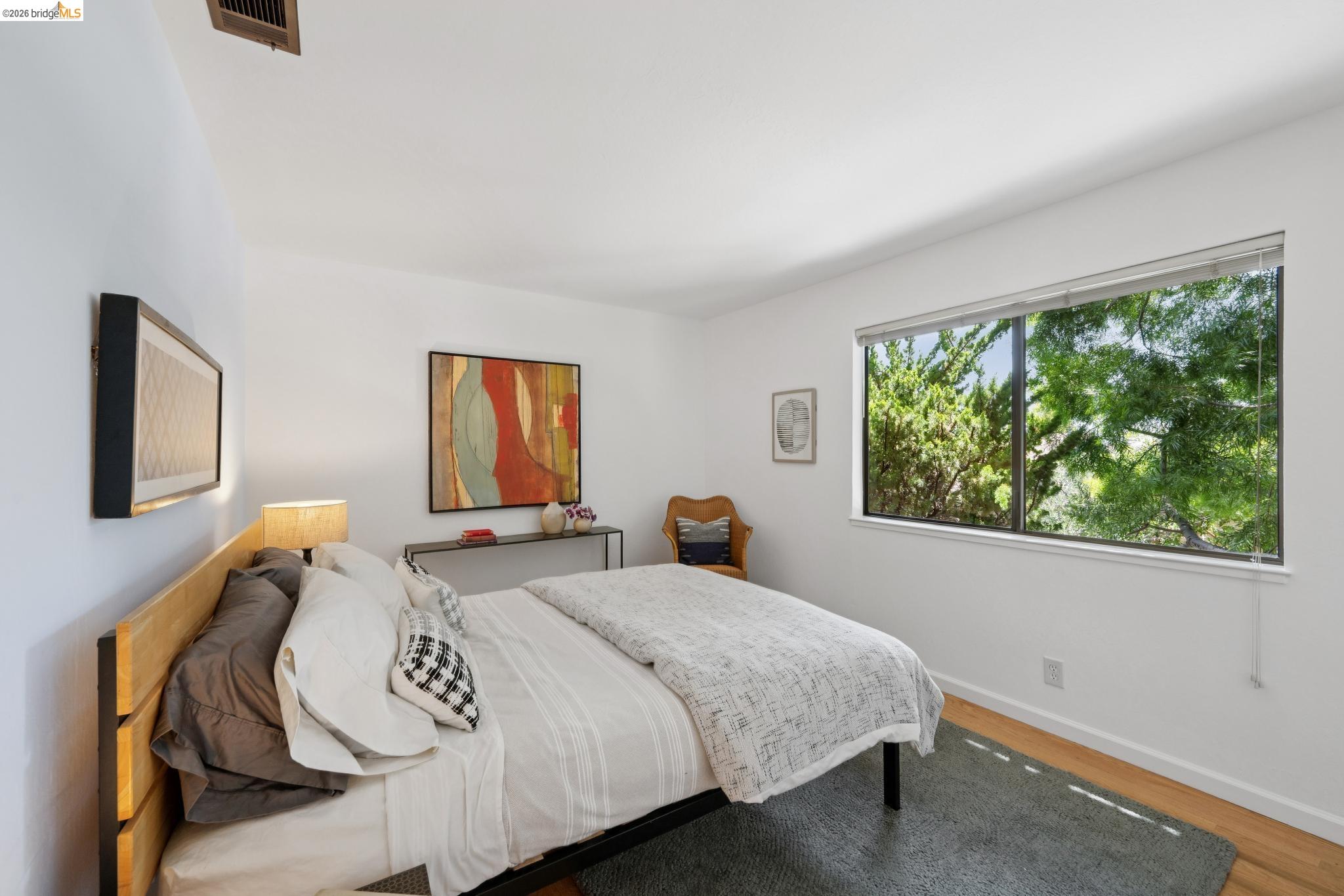 1340 Henry Street Berkeley, CA 94709 - Photo 34 of 52 Light-filled room featuring a large window with exterior foliage, white walls, and wood-finish flooring, good afternoon light.