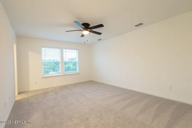 an empty room with a window and a fan