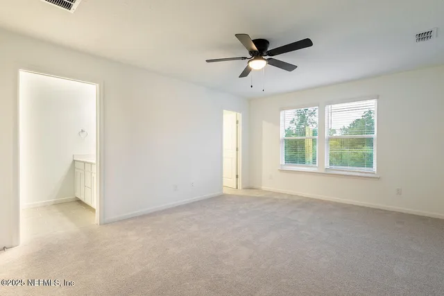 a view of a livingroom with a ceiling fan & windows