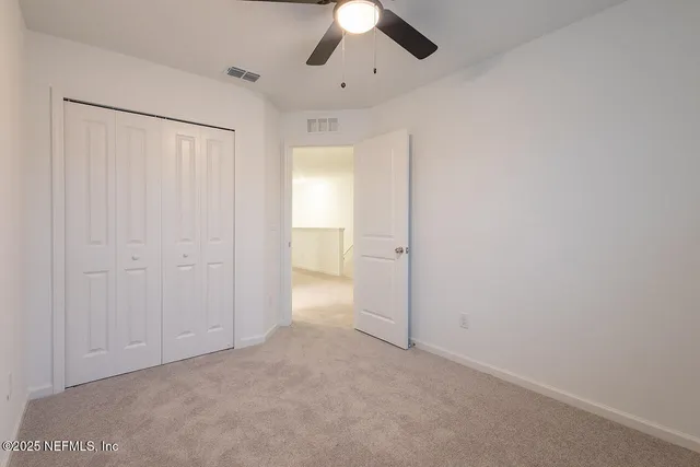 an empty room with a ceiling fan and a window