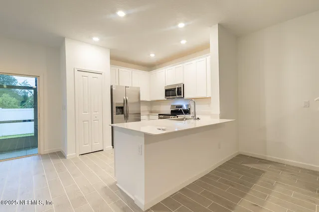 a kitchen with kitchen island a sink a stove a refrigerator cabinets and a dining table