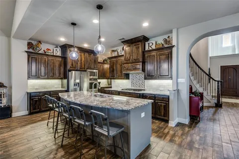 a kitchen with stainless steel appliances granite countertop a stove a refrigerator a oven a sink with a dining table and chairs