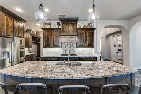 a kitchen with kitchen island granite countertop wooden cabinets and chairs