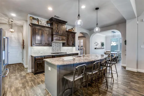 a kitchen with stainless steel appliances kitchen island granite countertop a table chairs sink and wooden floor