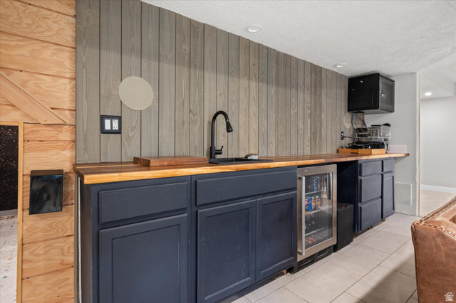 3359 Eurasian Crane Road Clinton, UT 84015 - Photo 39 of 71 Indoor wet bar with wood counters, wooden walls, beverage cooler, light tile patterned flooring, and recessed lighting
