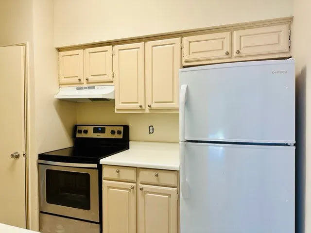 a white refrigerator freezer and a stove sitting inside of a kitchen