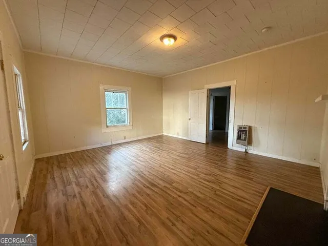 a view of an empty room with window and wooden floor
