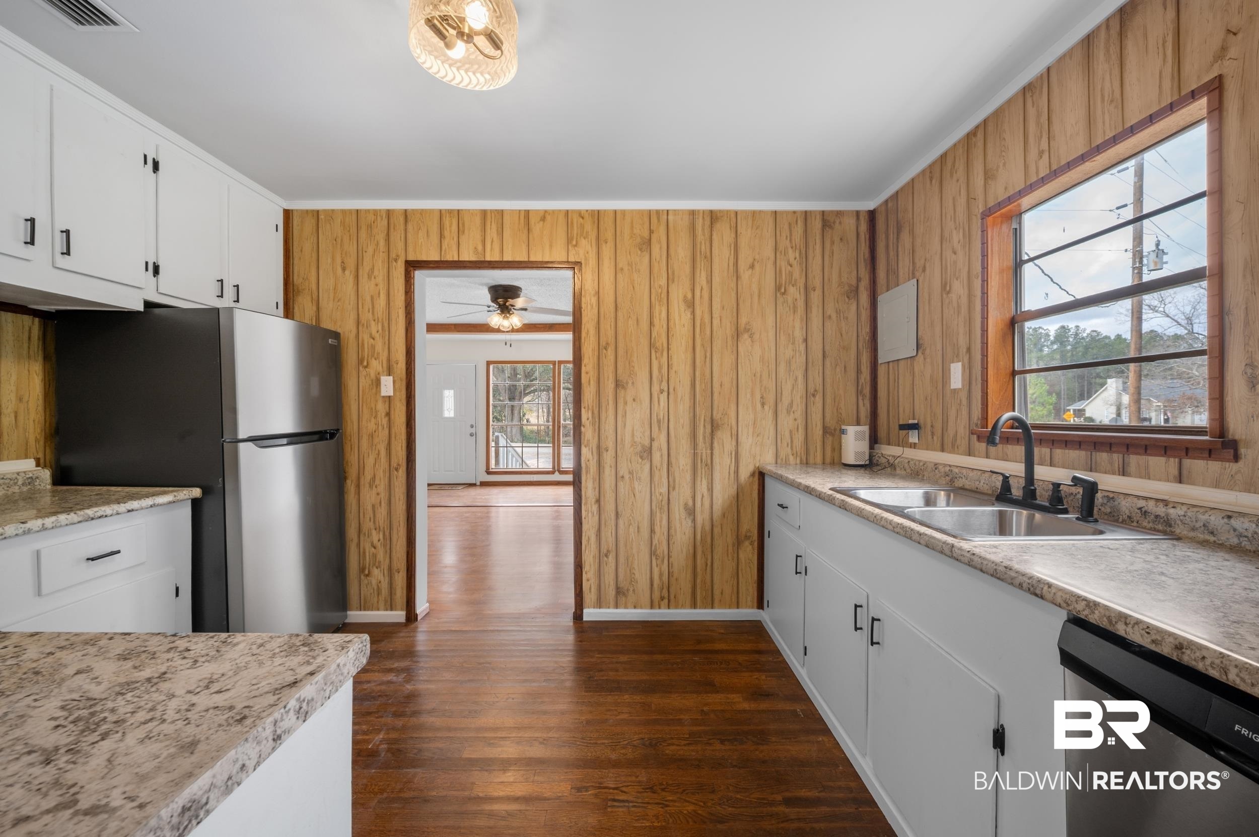 35780 Spring Road North Stapleton, AL 36578 - Photo 14 of 41 Kitchen with light countertops, stainless steel appliances, white cabinets, wooden walls, and dark wood-style flooring