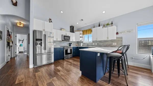 a kitchen with stainless steel appliances granite countertop a table chairs refrigerator and a sink