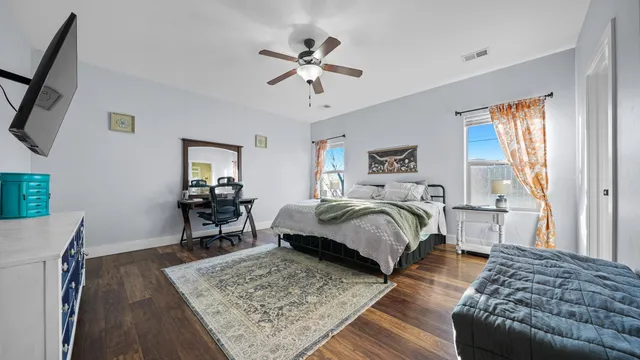 a bedroom with a bed a couch and a dresser with wooden floor