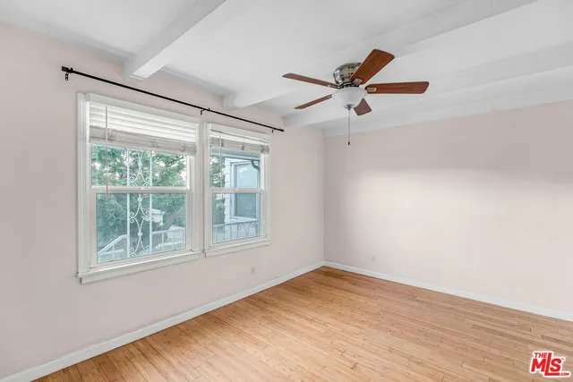 a view of empty room with wooden floor and fan