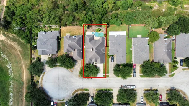 an aerial view of a house with outdoor space and trees all around