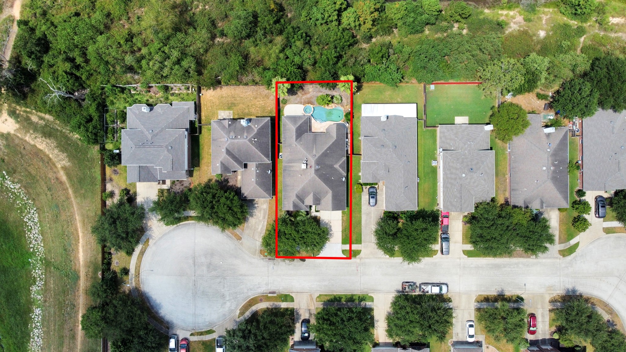 an aerial view of a house with outdoor space and trees all around