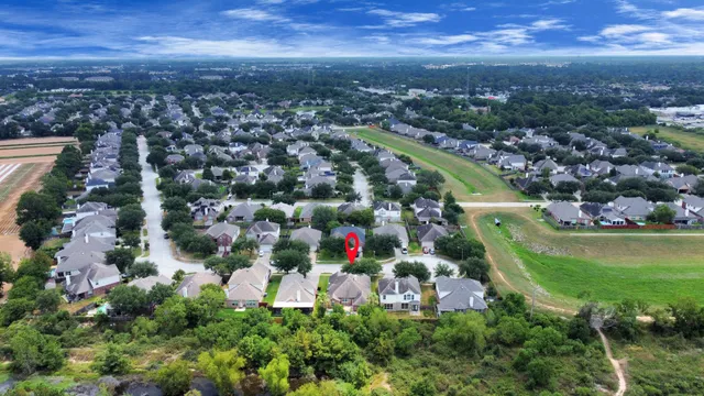 an aerial view of residential houses with outdoor space and trees