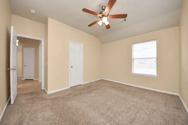 an empty room with chandelier fan and windows