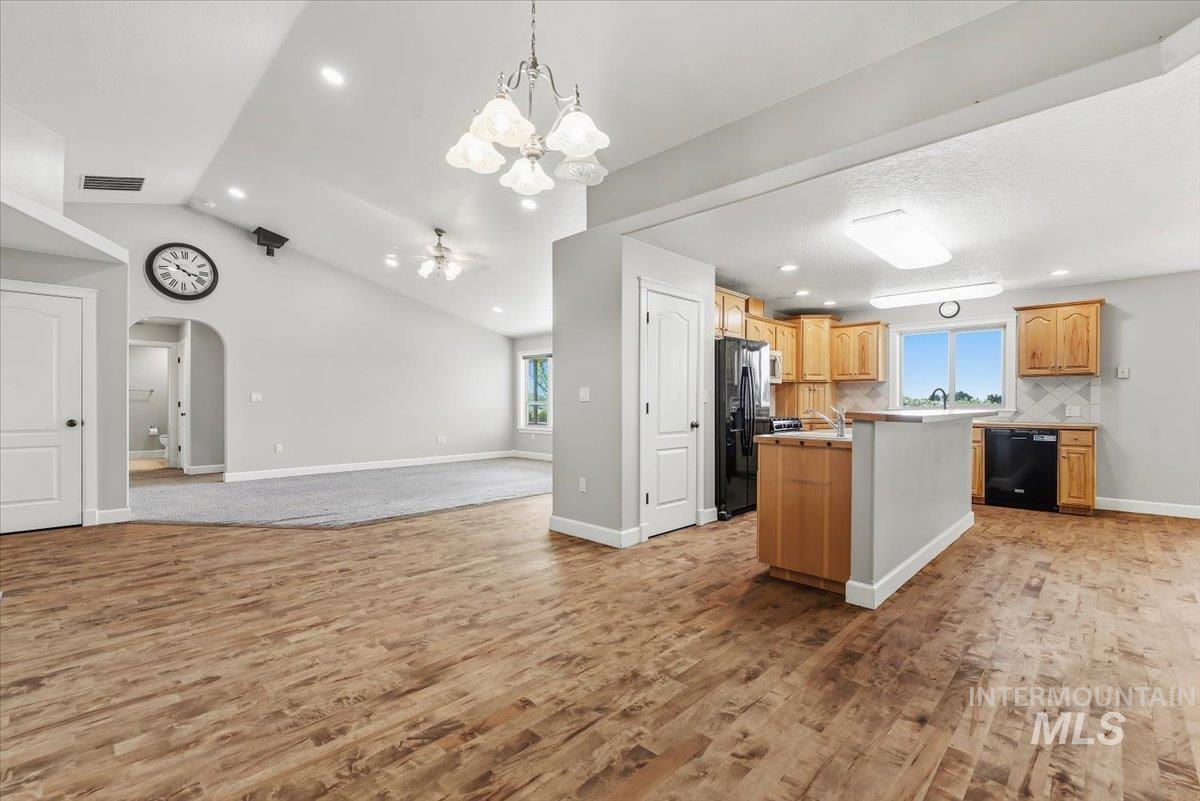 24240 Tiger Lane Caldwell, ID 83607 - Photo 10 of 50 Wood-finish flooring, vaulted ceiling, recessed lighting, kitchen island, and light wood cabinetry