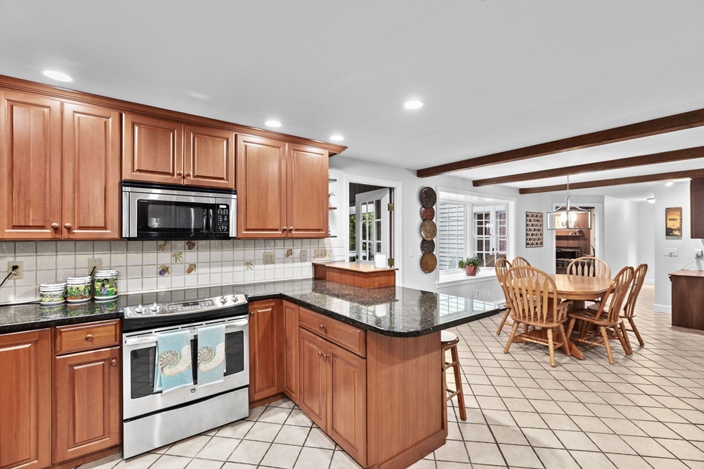 14 Camelot Drive Hingham, MA 02043 - Photo 4 of 34 a kitchen with stainless steel appliances granite countertop a stove a sink dishwasher a dining table and chairs with wooden floor