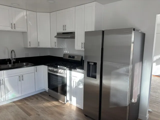 a kitchen with a refrigerator and white cabinets