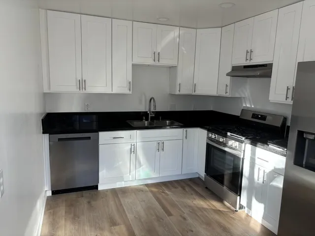 a kitchen with granite countertop white cabinets and black appliances
