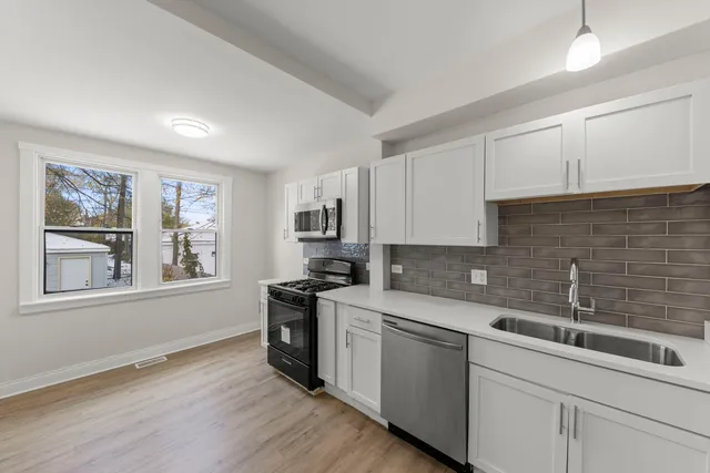 a kitchen with a sink cabinets wooden floor and stainless steel appliances