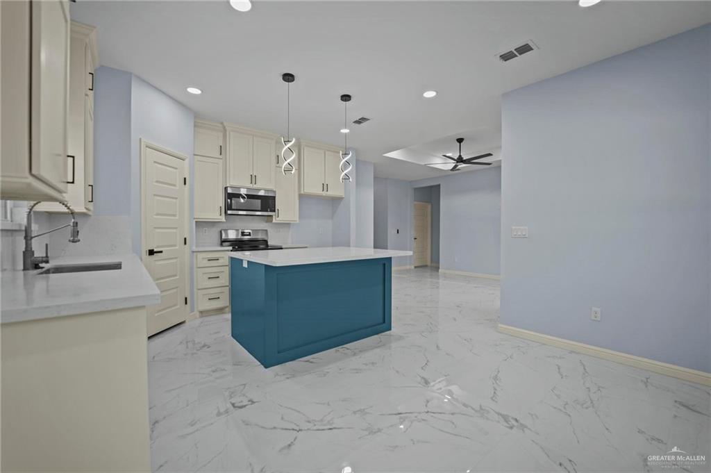 994 Rd Runner Street Rio Grande City, TX 78582 - Photo 4 of 17 a large kitchen with stainless steel appliances a sink stove and cabinets