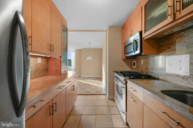 a kitchen with stainless steel appliances granite countertop a refrigerator a stove and a sink