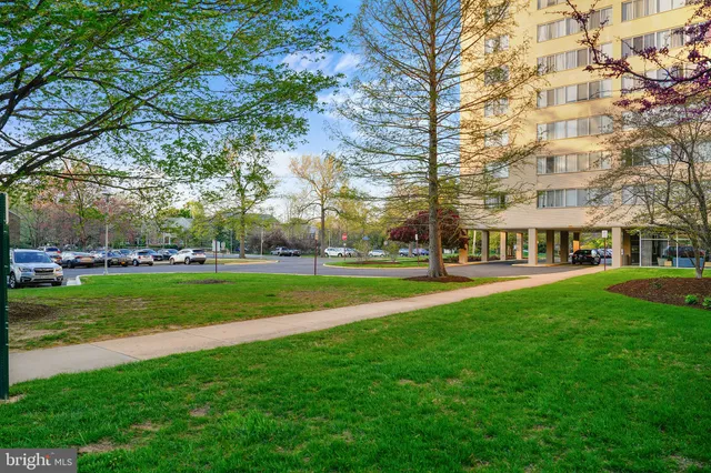 a view of a building with a big yard and large trees