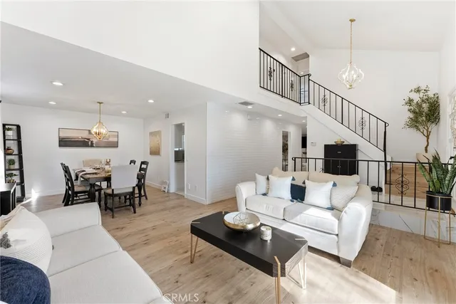 a living room with furniture kitchen view and a wooden floor