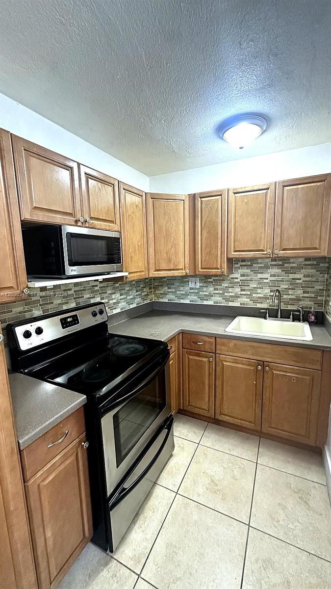 4444 Southwest 67th Avenue, Unit 6 Miami, FL 33155 - Photo 5 of 11 a kitchen with kitchen island granite countertop a sink cabinets and stainless steel appliances
