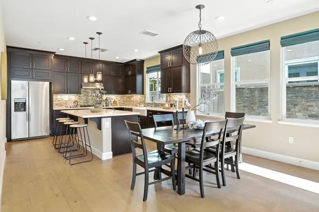 a dining room with stainless steel appliances granite countertop a table chairs and a view of kitchen
