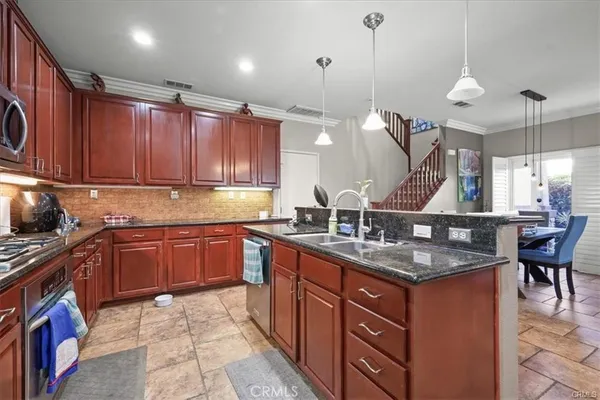 a kitchen with granite countertop a sink a counter space appliances and cabinets