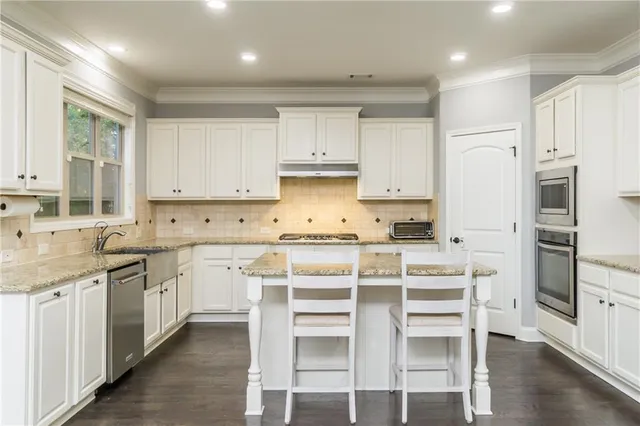 a kitchen with granite countertop white cabinets and stainless steel appliances