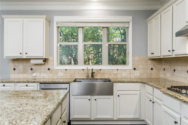 a kitchen with granite countertop a sink window and cabinets