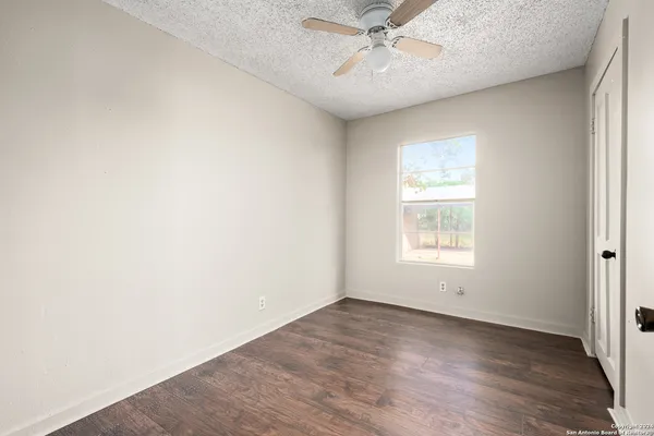 an empty room with a window and a fan