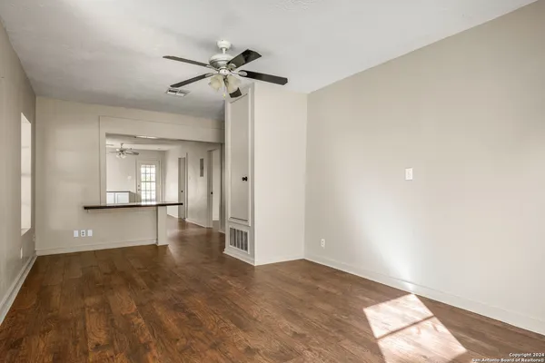 a view of empty room with wooden floor and fan