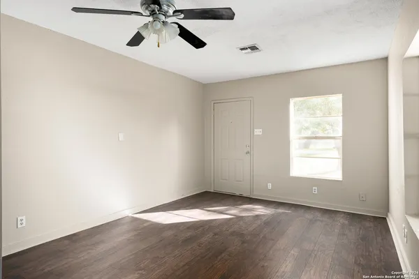 an empty room with a window and a ceiling fan