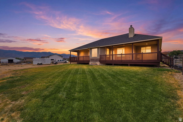 2567 West Rim Rock Drive Stockton, UT 84071 - Photo 51 of 64 Expansive rear yard featuring a manicured lawn, a full-length covered deck, and a wood railing with stairs