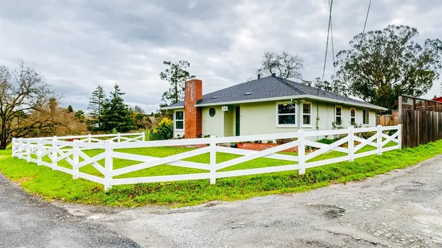 a view of a white house with a yard and potted plants