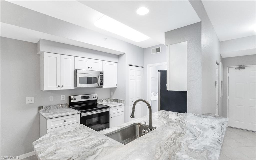 4635 St Croix Lane, Unit 1215 Naples, FL 34109 - Photo 11 of 22 a kitchen with granite countertop a stove top oven microwave and refrigerator