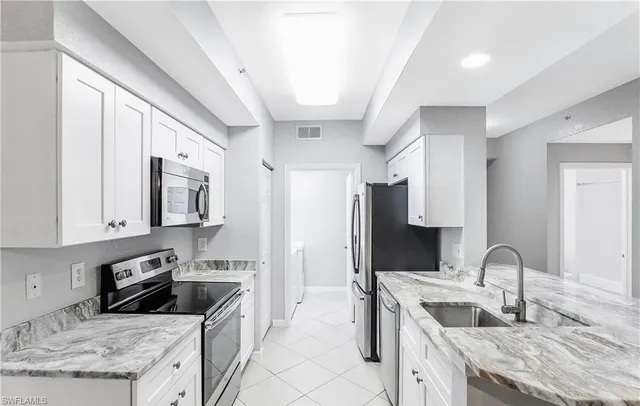 a kitchen with granite countertop a stove top oven microwave and refrigerator