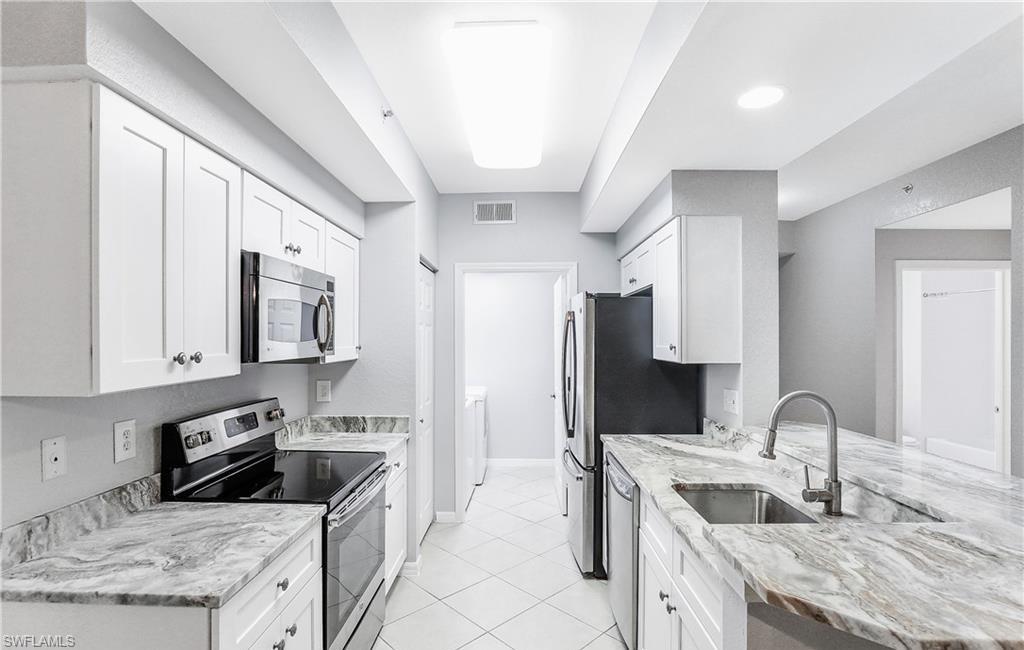 4635 St Croix Lane, Unit 1215 Naples, FL 34109 - Photo 9 of 22 a kitchen with stainless steel appliances granite countertop a sink stove and refrigerator