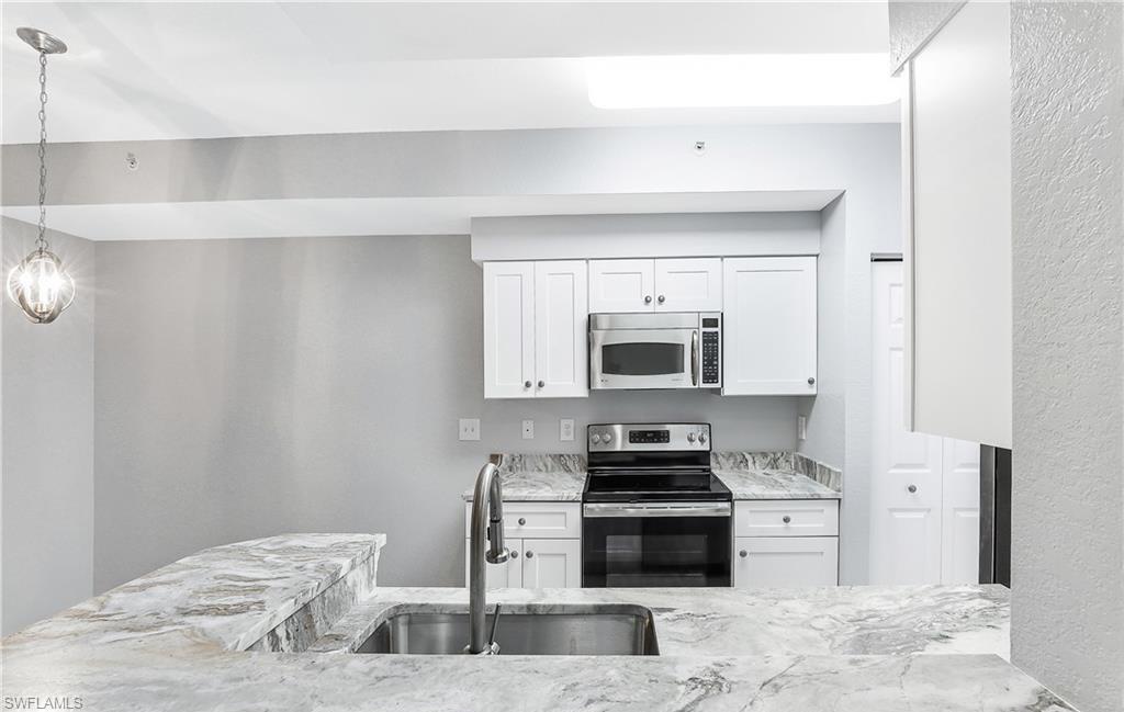 4635 St Croix Lane, Unit 1215 Naples, FL 34109 - Photo 10 of 22 a kitchen with stainless steel appliances a stove microwave and sink