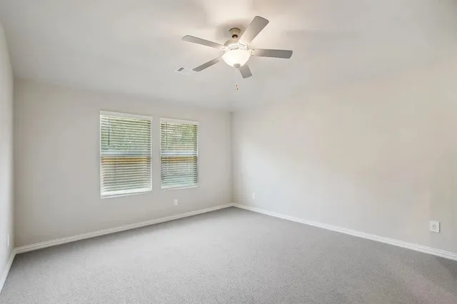 an empty room with a window and a ceiling fan