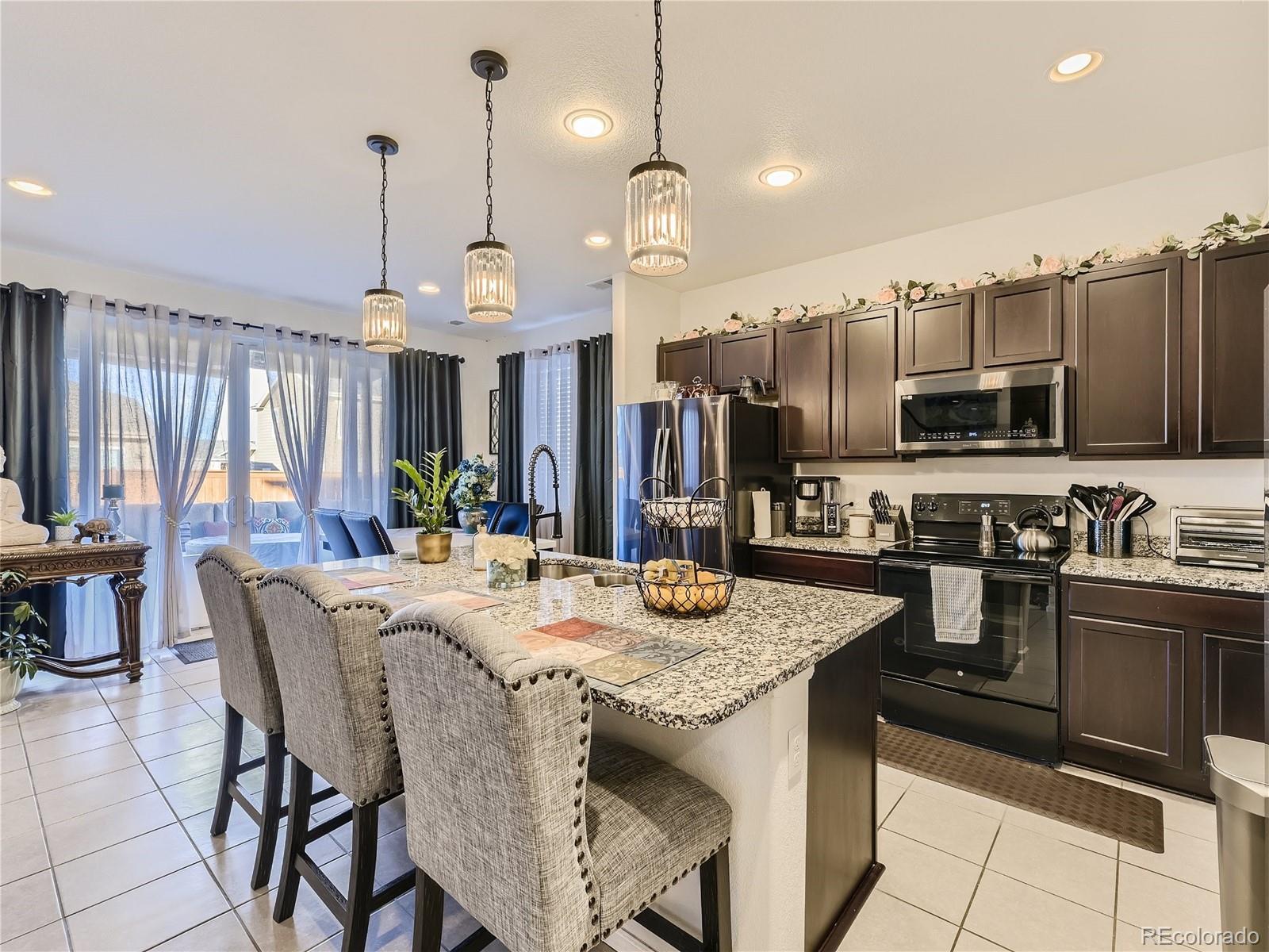 219 South Kellerman Street Aurora, CO 80018 - Photo 9 of 28 a kitchen with stainless steel appliances kitchen island granite countertop a stove a sink a refrigerator a dining table and chairs with wooden floor