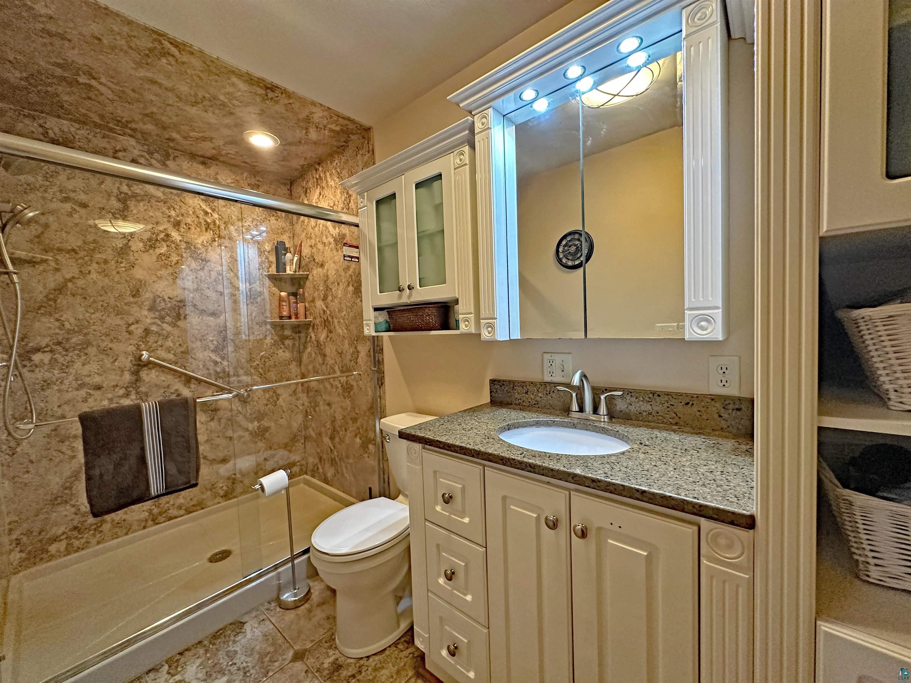 5865 Eastview Road Iron River, WI 54847 - Photo 25 of 41 Bathroom featuring a shower with shower door, toilet, vanity, and tile patterned floors