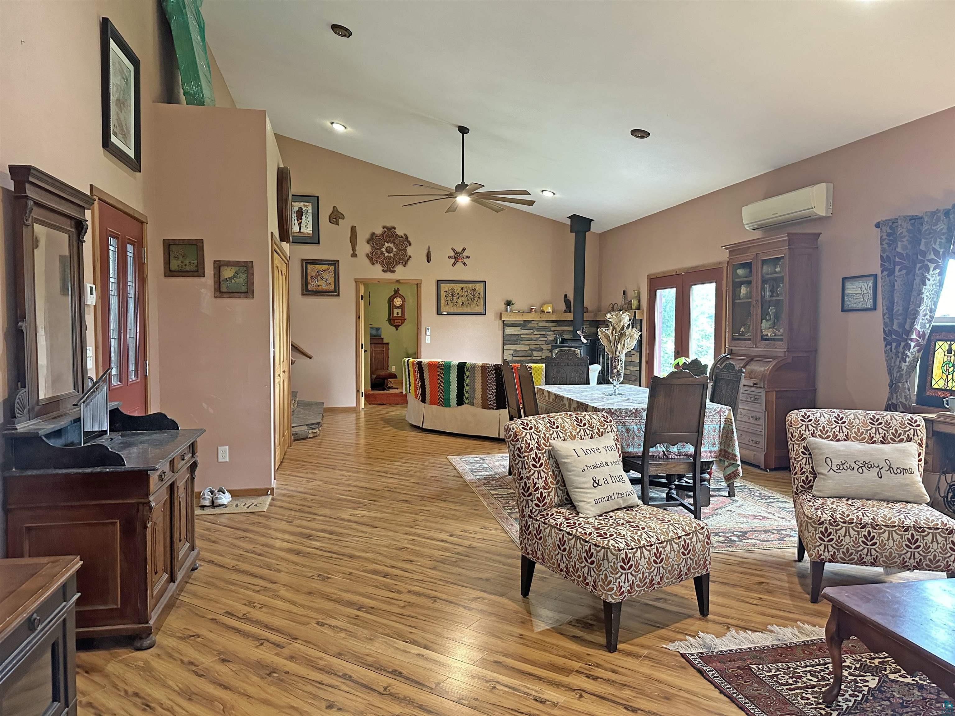 5865 Eastview Road Iron River, WI 54847 - Photo 3 of 41 Living room with high vaulted ceiling, light hardwood / wood-style floors, a wall mounted air conditioner, and a wood stove